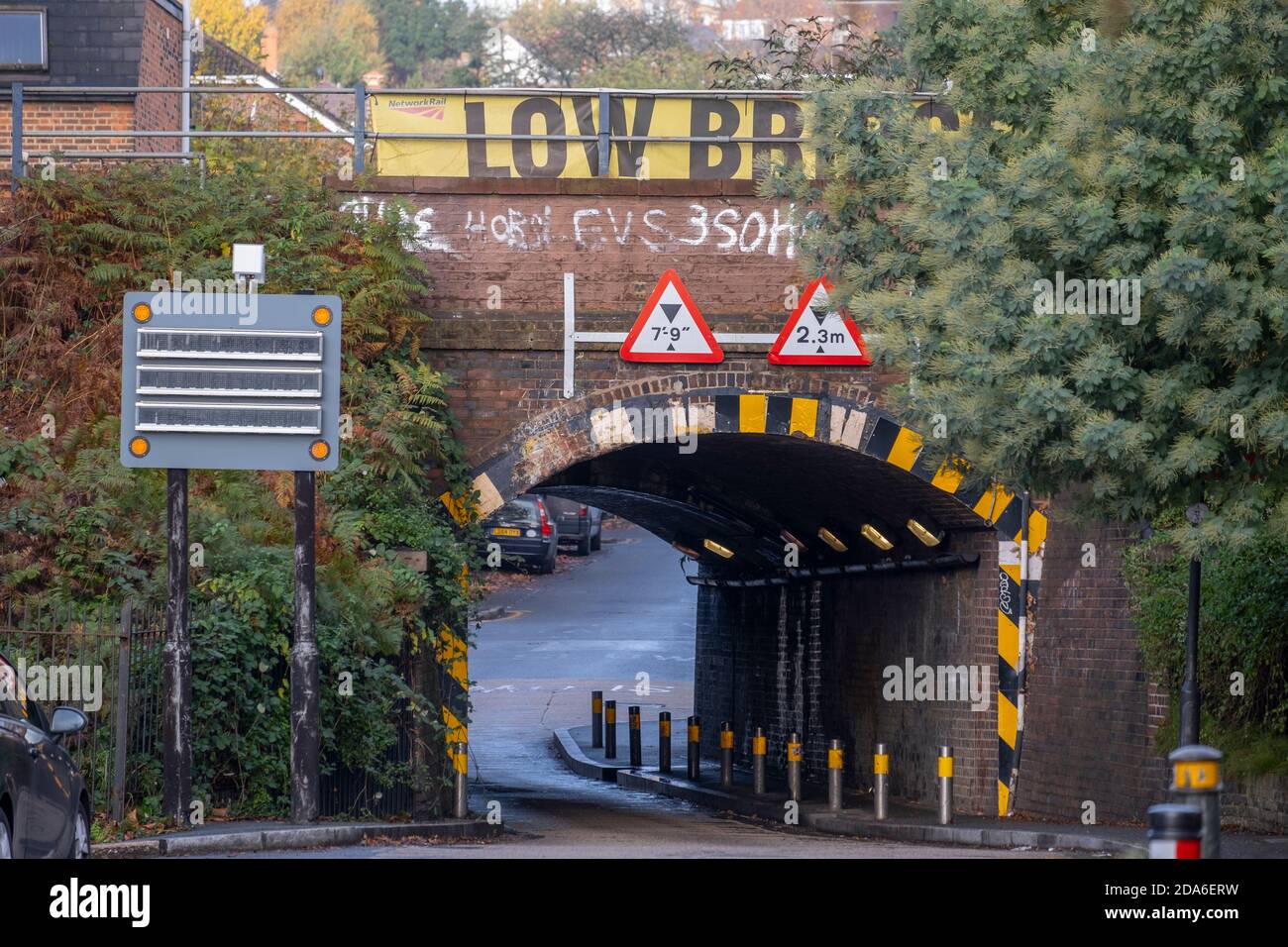 Lower Downs Road, Wimbledon, Londra, Regno Unito. 10 novembre 2020. Un rapporto sulla rete ferroviaria mostra che questo ponte ferroviario di Wimbledon è uno dei "più scolpiti" a Londra, entrando al 2° e colpendo 11 volte nel 2019-20. E 'anche il decimo eguale più bashed in Gran Bretagna. Sopra questo stretto ponte ad arco si trovano quattro binari ferroviari, due per i treni pendolari e due per i treni espressi da e per London Waterloo verso il sud-ovest dell'Inghilterra. L'insegna del parapetto di Low Bridge è parzialmente oscurata dal fogliame dell'albero sull'approccio meridionale. Credit: Malcolm Park/Alamy Live News. Foto Stock