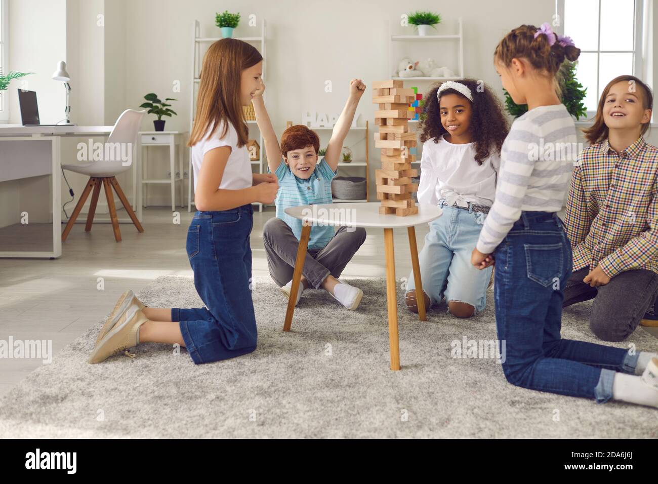 Gruppo di bambini felici che giocano legno blocco torre impilando gioco a casa o nel club di svago dopo la scuola Foto Stock