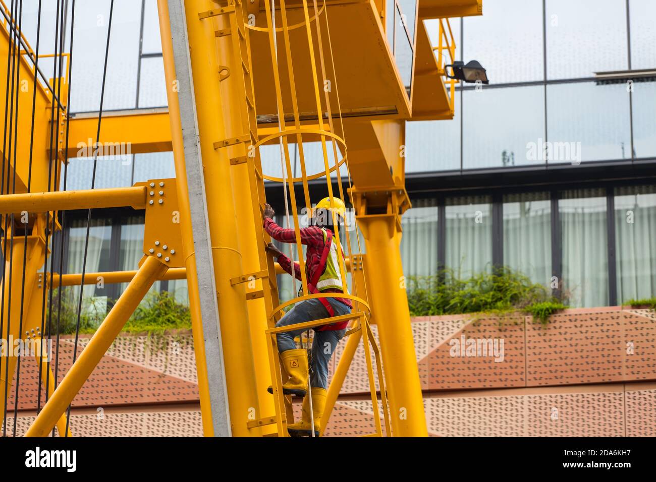 L'operatore indiano sta salendo la scala verticale su una gru a portale per lavori di costruzione nell'area urbana. Singapore, 2020. Foto Stock