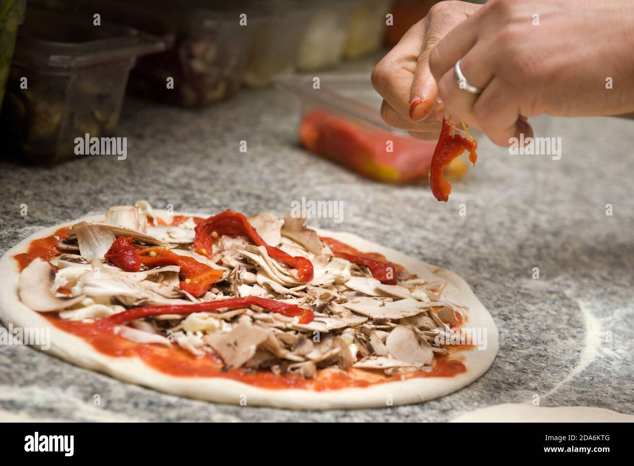 il pizzaiolo prepara una pizza con porchetta e rosso peperoni Foto Stock
