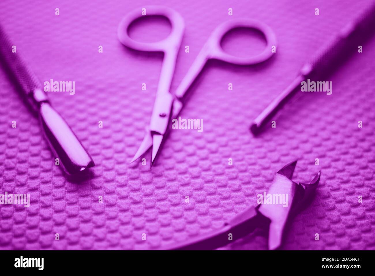 Set di attrezzi per manicure professionali su tavola bianca. Tono violetto. Foto Stock