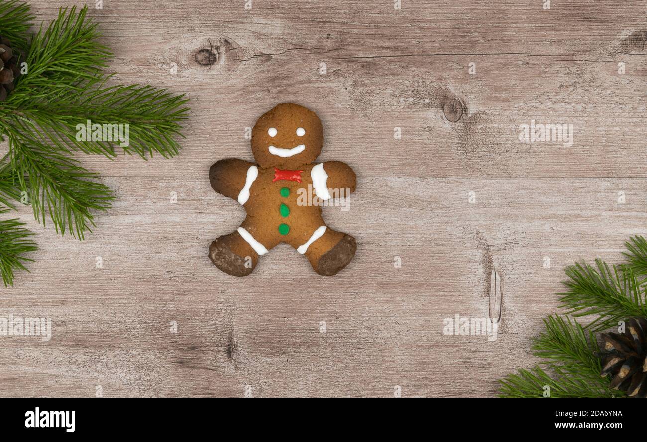 Pan di zenzero su una superficie di legno decorata con rami di abete rosso. Biscotti di pan di zenzero di Natale tradizionali. Dolcetti di festa fatti a mano. Foto Stock