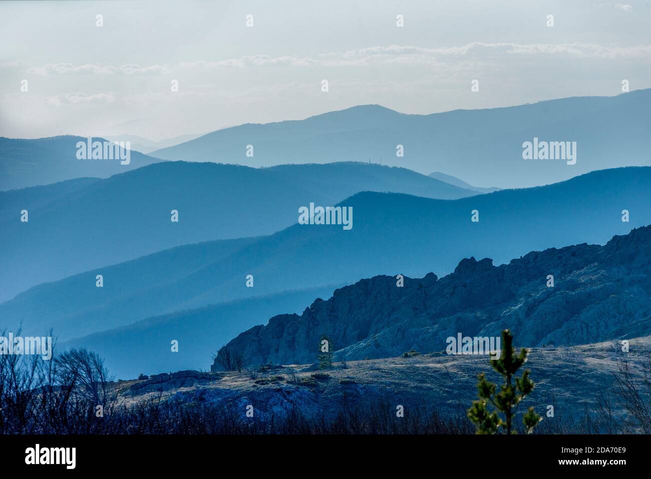 Strati di colline ondulate nei toni del verde e del blu in lontananza - grande catena rocciosa di montagna Foto Stock