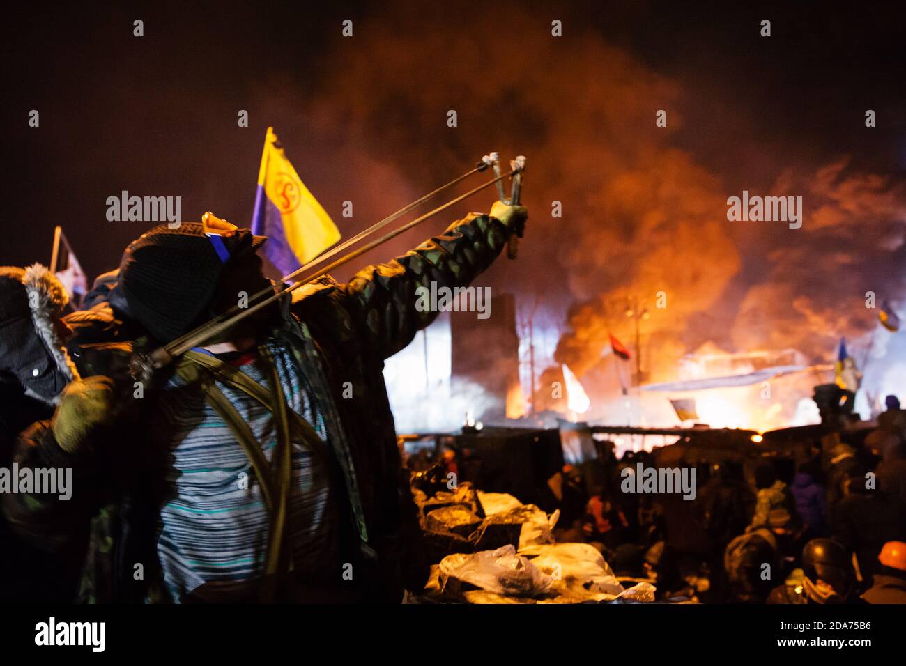 KIEV, UCRAINA - 24 gennaio 2014: Proteste di massa contro il governo nel centro della capitale Ucraina Kiev. Il guerriero della resistenza popolare spara un colpo di schiaffo verso le truppe di governo su Hrushevskoho St. Foto Stock