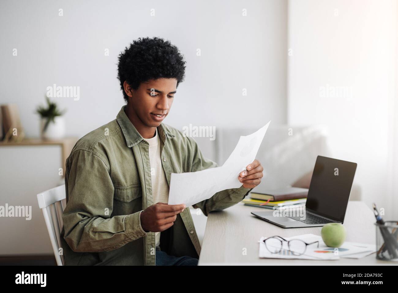 Teenager nero che studia da remoto su un computer portatile, lavora al lavoro di formazione, coordina il suo progetto scolastico con il tutor a casa Foto Stock