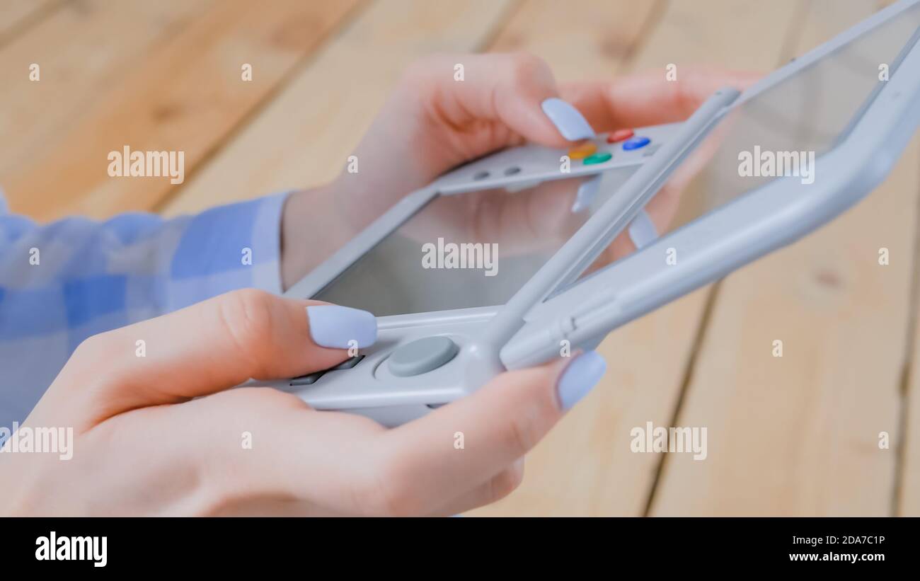 Vista ravvicinata delle mani dei giocatori che usano la console di gioco portatile grigia a casa. Giochi, hobby, tecnologia, intrattenimento, portatile, videogiochi e. Foto Stock