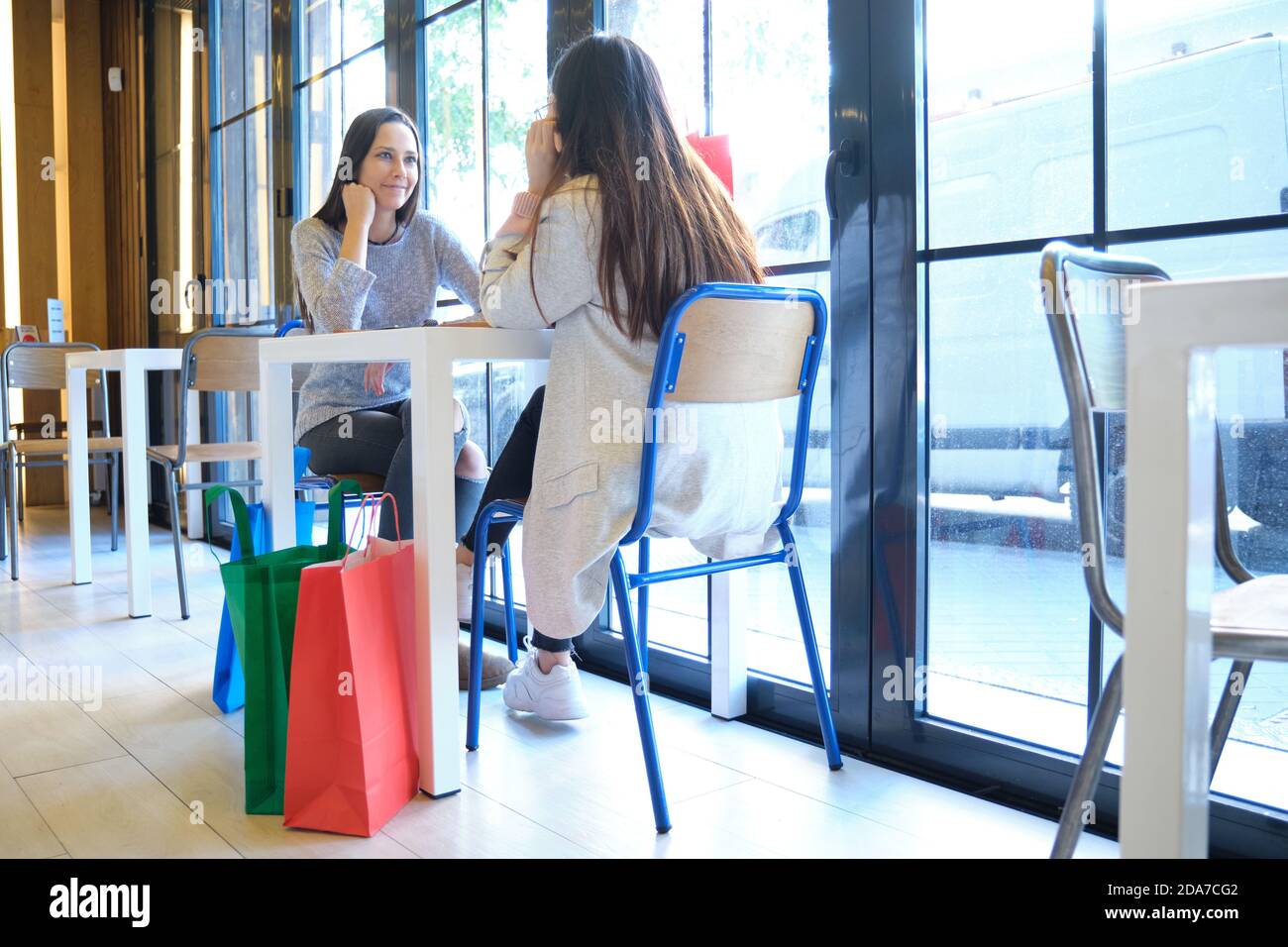 Due amiche in una caffetteria dopo lo shopping. Donne caucasiche e asiatiche in un ristorante. Foto Stock