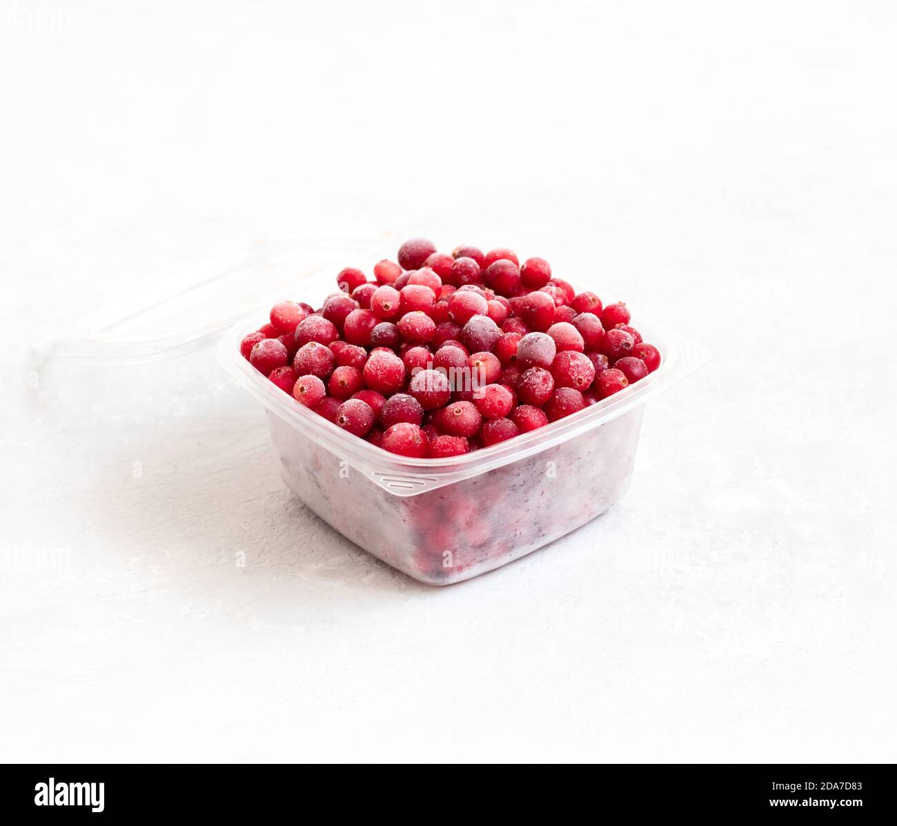 Mirtilli congelati in un contenitore di plastica su fondo bianco. Conservazione di alimenti surgelati. Vista laterale. Foto Stock