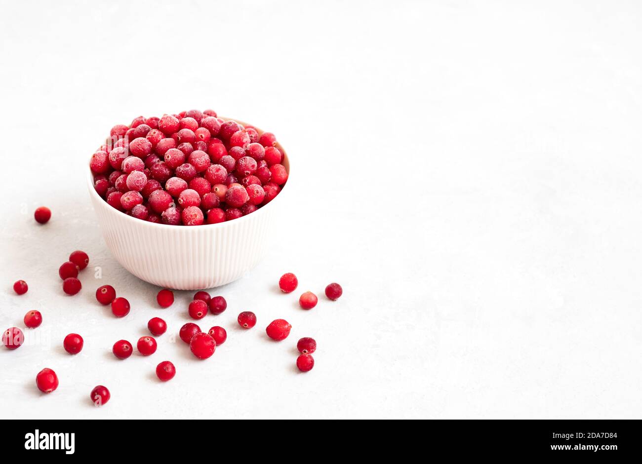 Mirtilli rossi congelati in un recipiente. Bacche rosse surgelate su sfondo bianco. Cibo biologico vegetariano. Vista laterale. Spazio di copia. Foto Stock