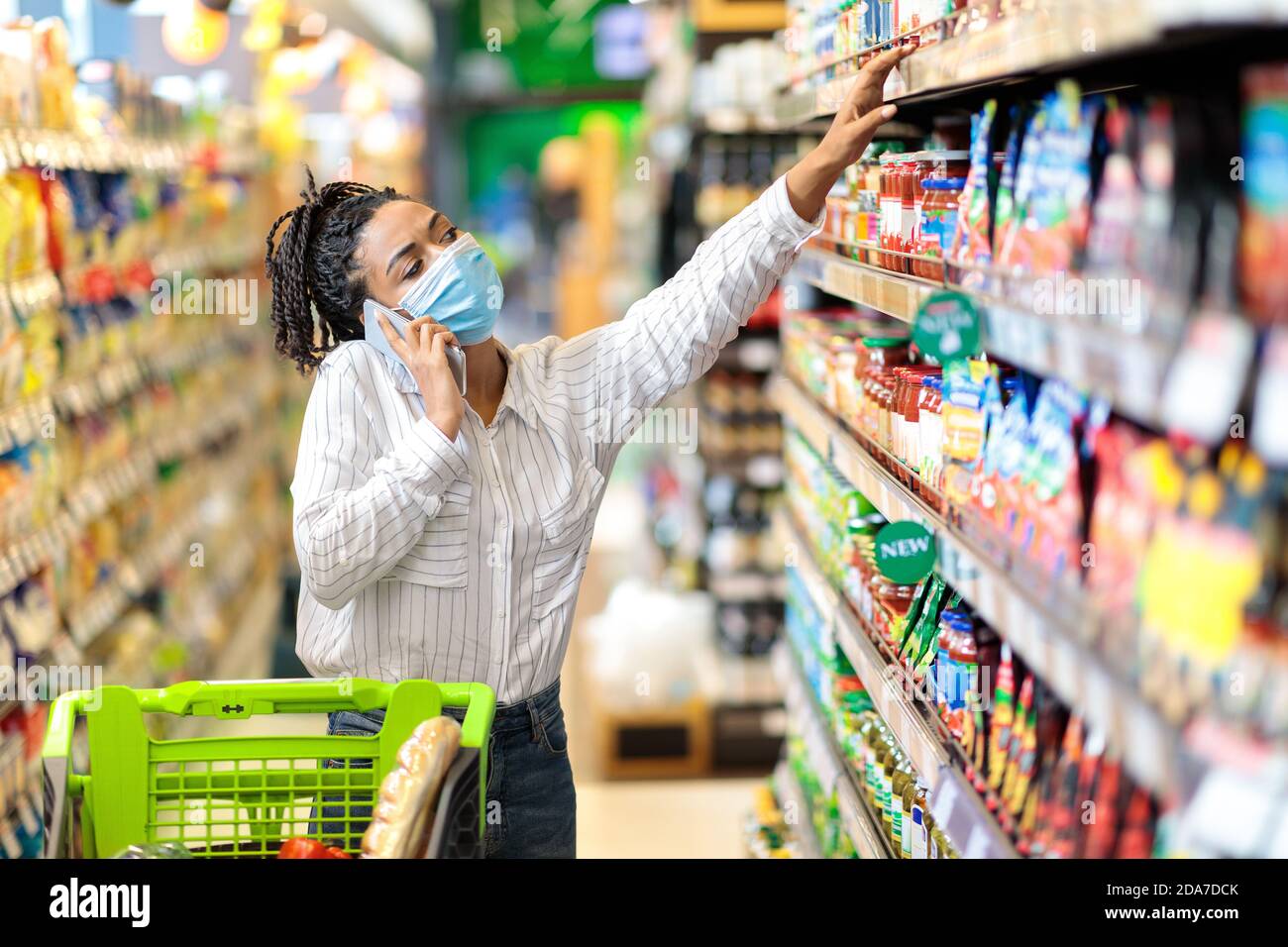 Black Lady che parla sul telefono che acquista cibo nel negozio Supermarket Foto Stock