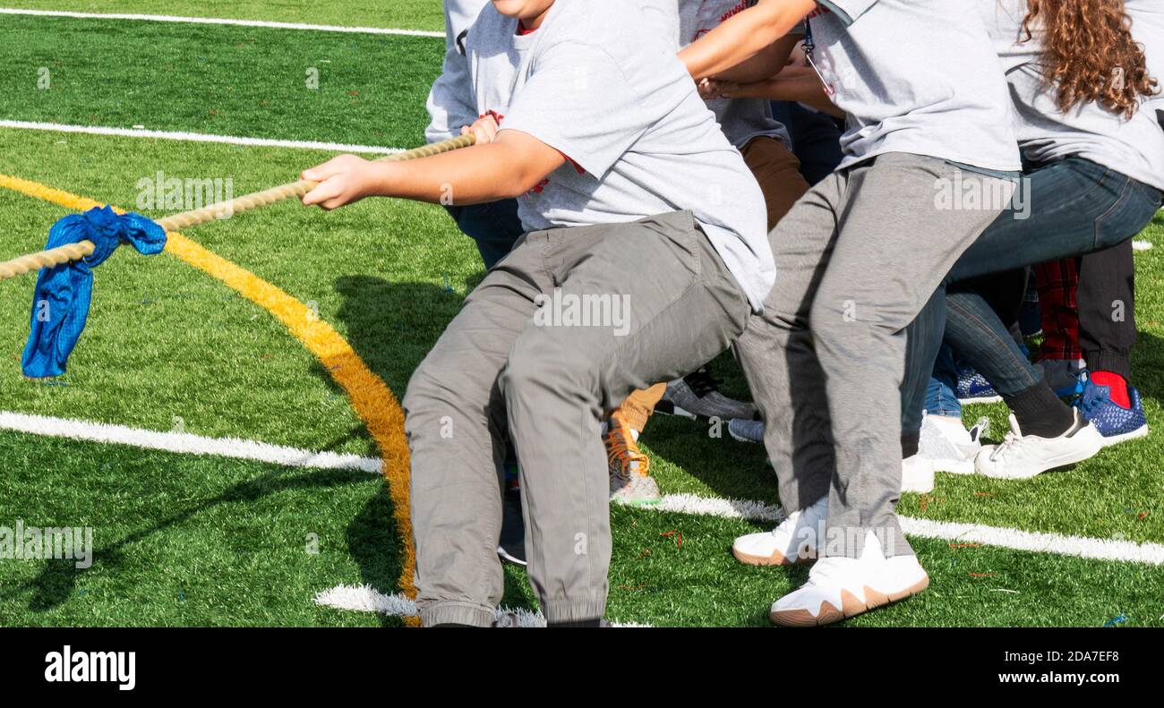 Adolescenti che tirano una corda durante un rimorchiatore di gioco di guerra in classe palestra. Foto Stock