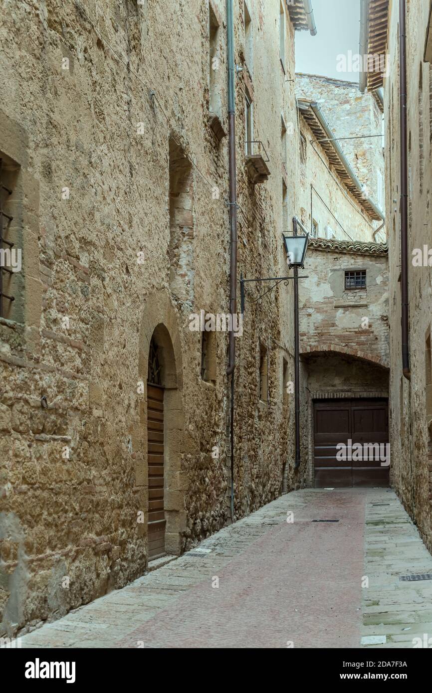 Paesaggio urbano con vecchi edifici su un vicolo stretto in cima alla collina storica cittadina, girato in luce brillante a Pienza, Siena, Toscana, Italia Foto Stock