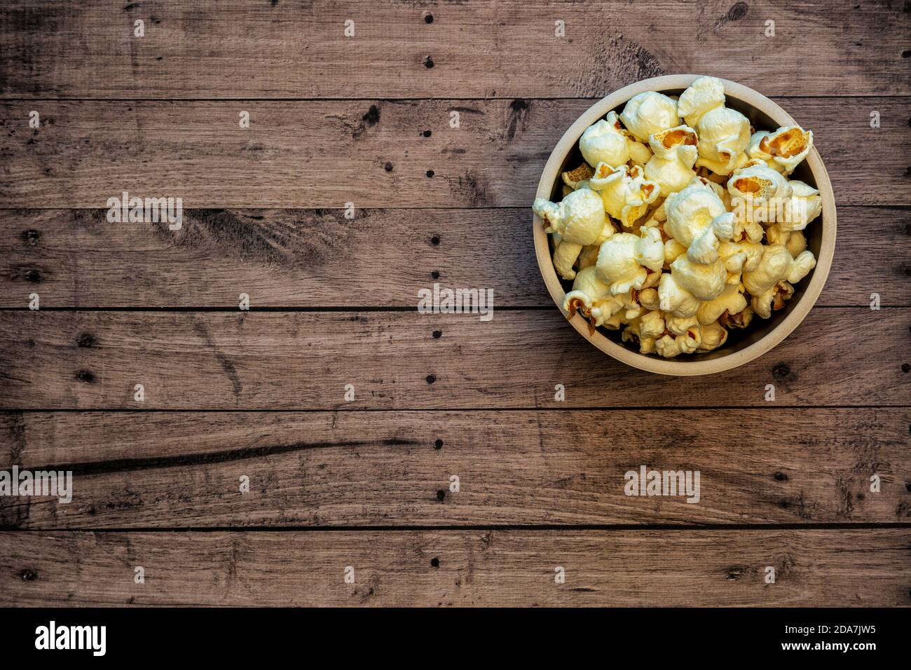 Ciotola di popcorn con sfondo in legno, spazio di copia e vista dall'alto Foto Stock