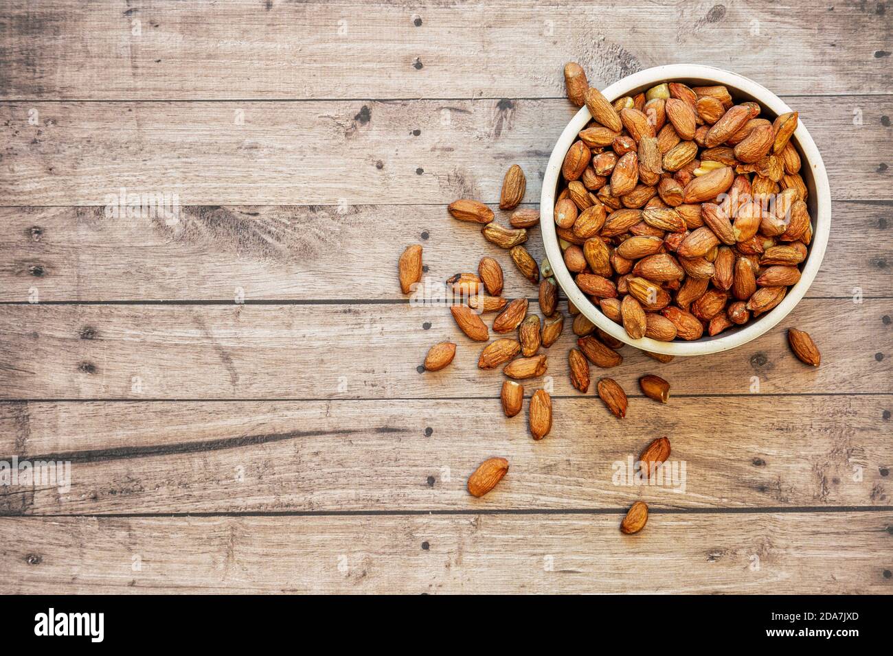 Ciotola di arachidi con sfondo in legno, spazio per la copia e vista dall'alto Foto Stock
