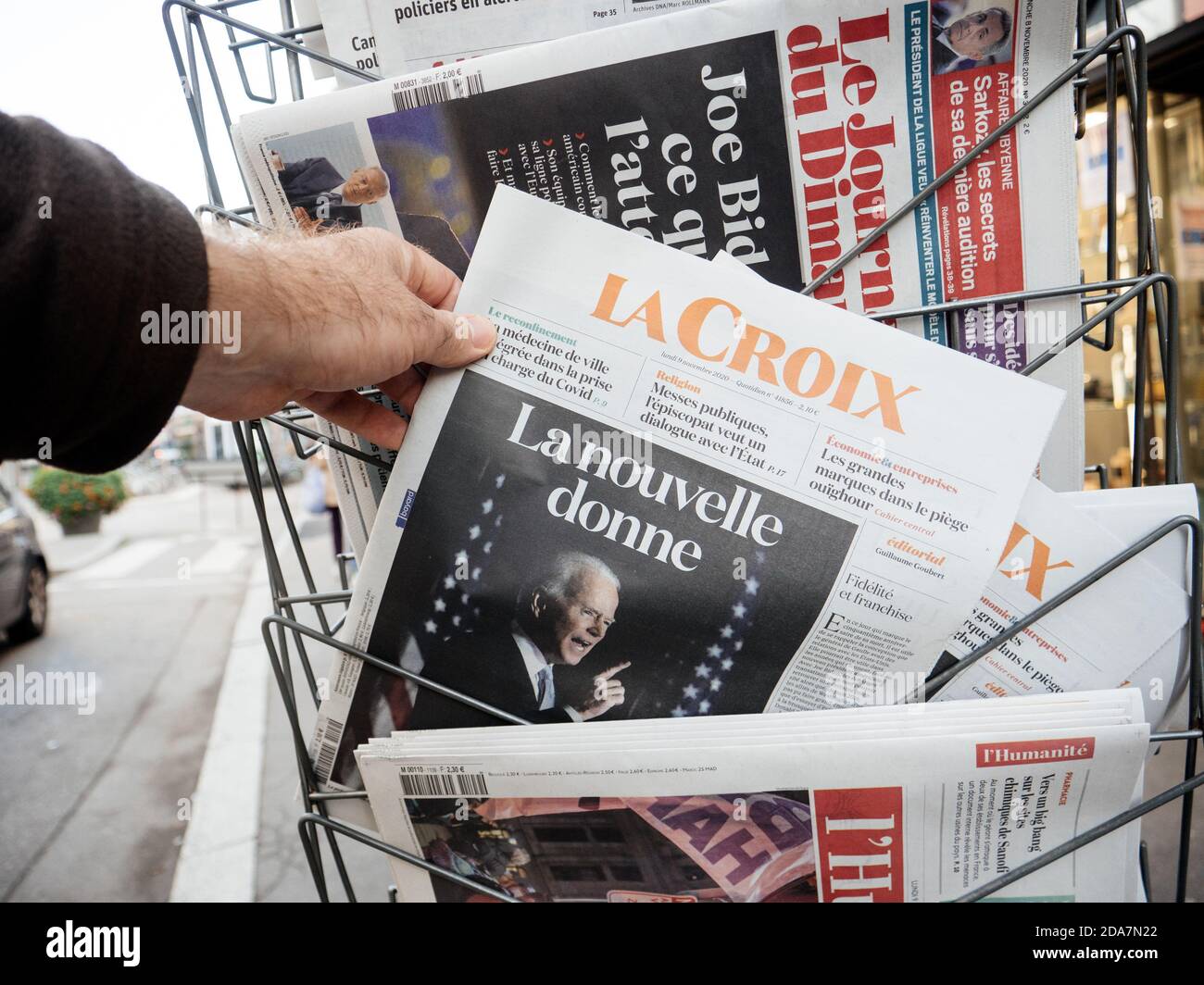 Parigi, Francia - 9 novembre 2020: POV uomo mano acquistare presso il chiosco stampa la Croix giornale con titolo il nuovo accordo - con la proiezione di Joe Biden vittoria delle elezioni presidenziali statunitensi contro l'ex-presidente Donald Trump Foto Stock