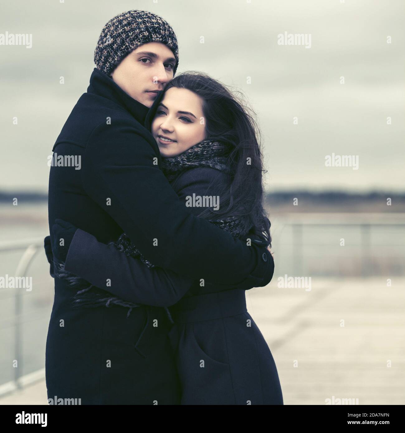 Felice moda giovane coppia in amore abbracciando outdoor elegante uomo e donna che indossa cappotti classico beanie e sciarpa Foto Stock