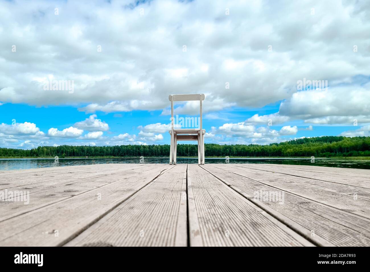 Sedia vuota in legno bianco presso il molo del lago di fronte a una splendida vista. Foto Stock