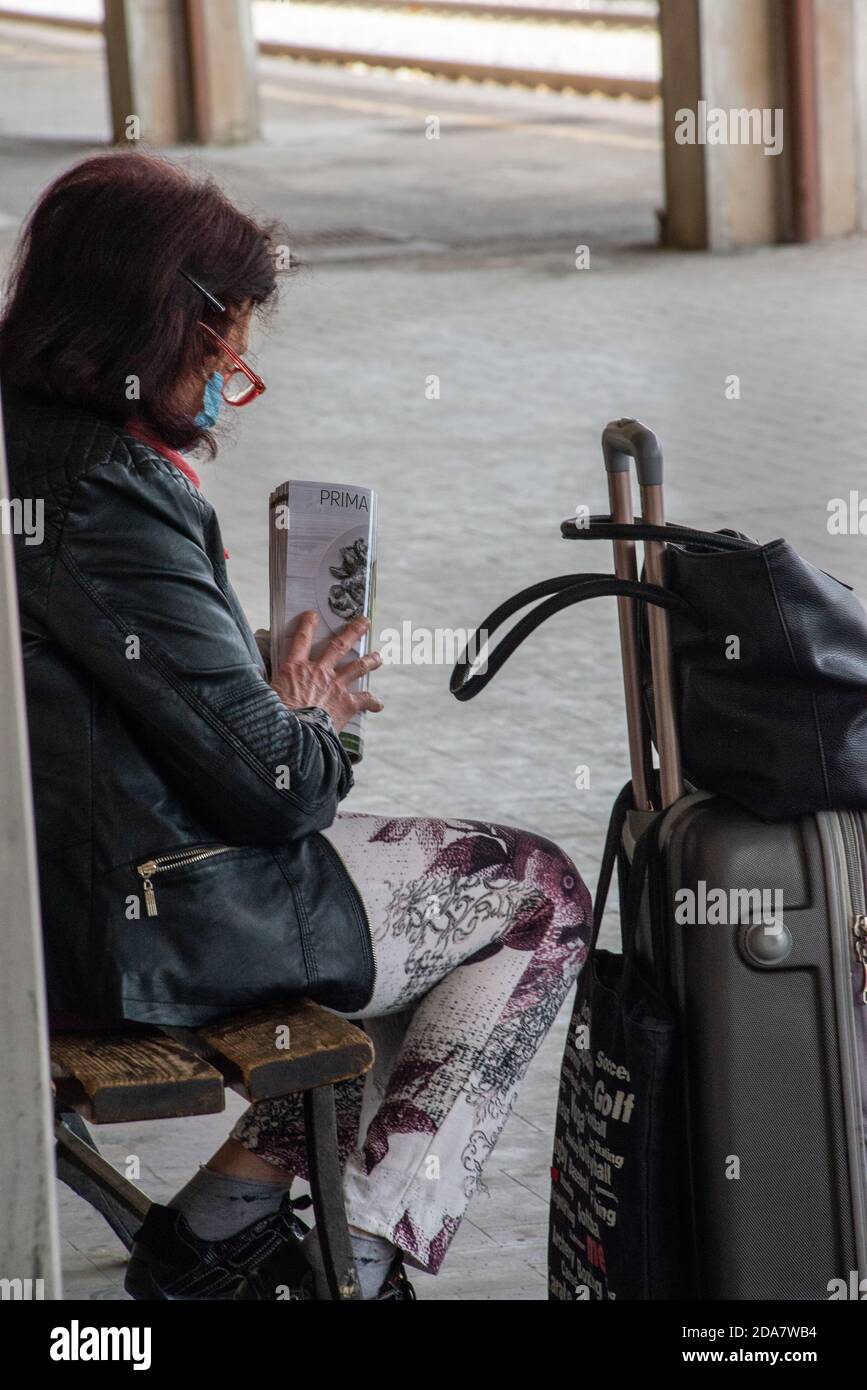 terni, italia maggio 29 2020:donna in attesa di treno per lasciare tenere giornale e ha maschera per la covid emergenza Foto Stock