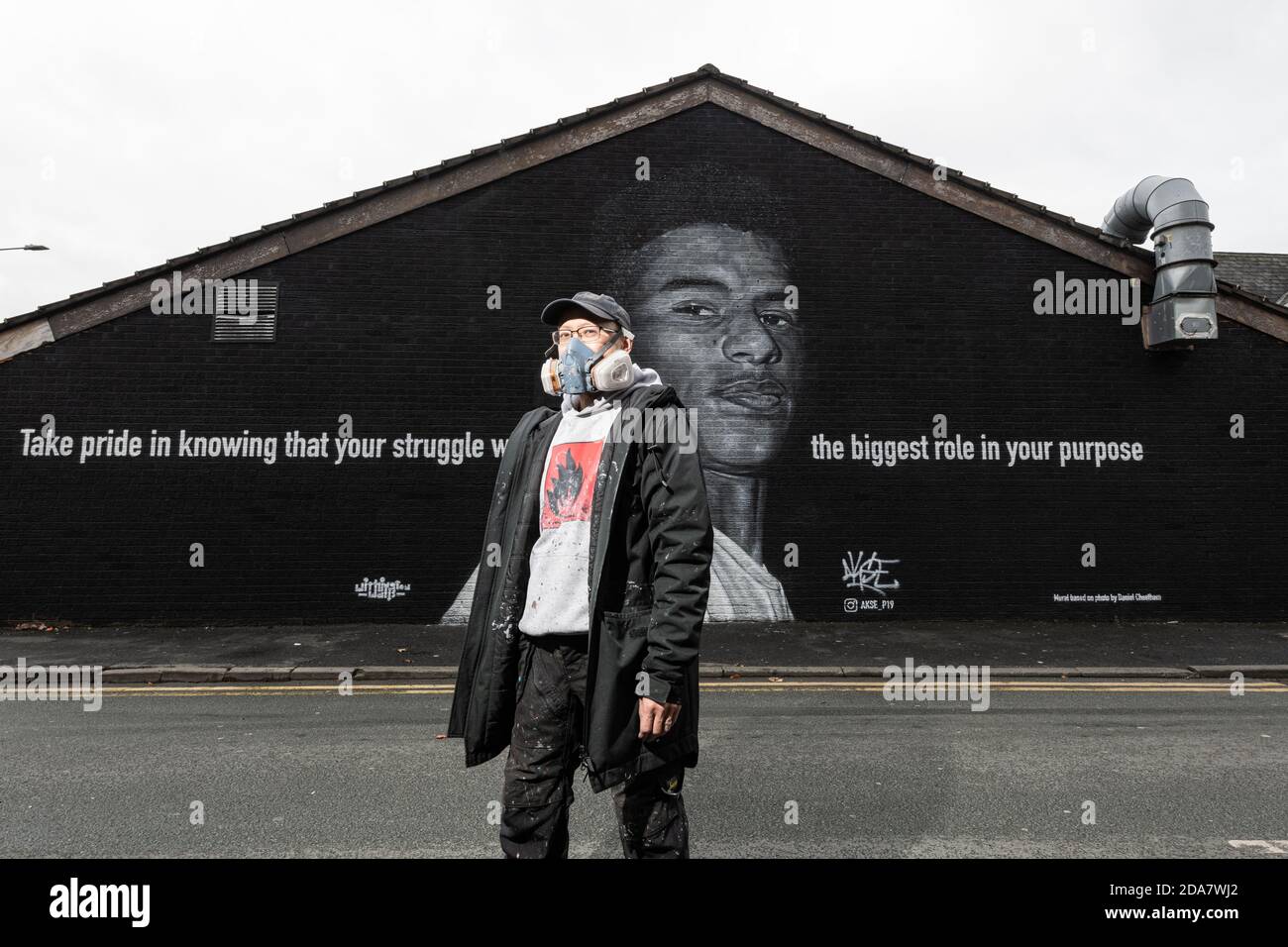 Un artista di strada AKSE 19, che si trova di fronte al murale della star del calcio Marcus Rashford. Il pezzo è stato completato 2 giorni dopo la campagna di Rashford per elevare la povertà alimentare infantile, costringendo il governo britannico a una seconda inversione a U sulla questione sociale. Foto Stock