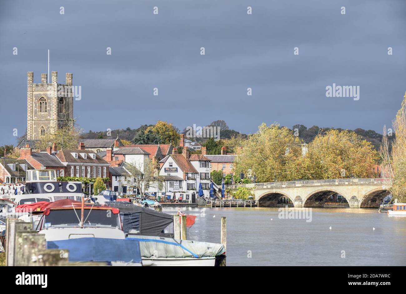 Un cielo scuro sopra edifici illuminati al sole in Henley-on-Thames su un caldo giorno d'autunno Foto Stock