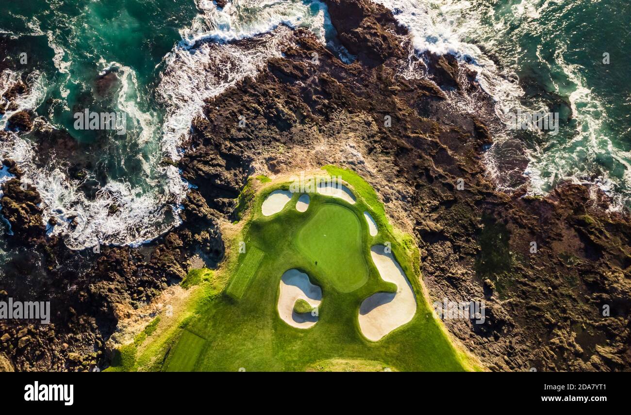 Vista sul drone del campo da golf della spiaggia di ciottoli vicino l'oceano con le onde che colpiscono le rocce a bassa marea A Monterey, California Foto Stock