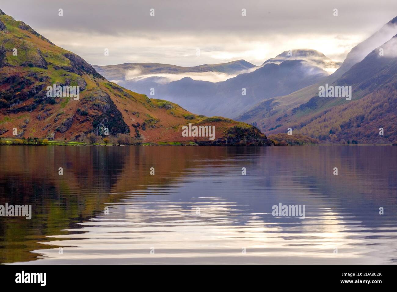 Crummock Water nel nord-ovest Lake District National Park, Cumbria. Le campane intorno a Buttermere in lontananza Foto Stock