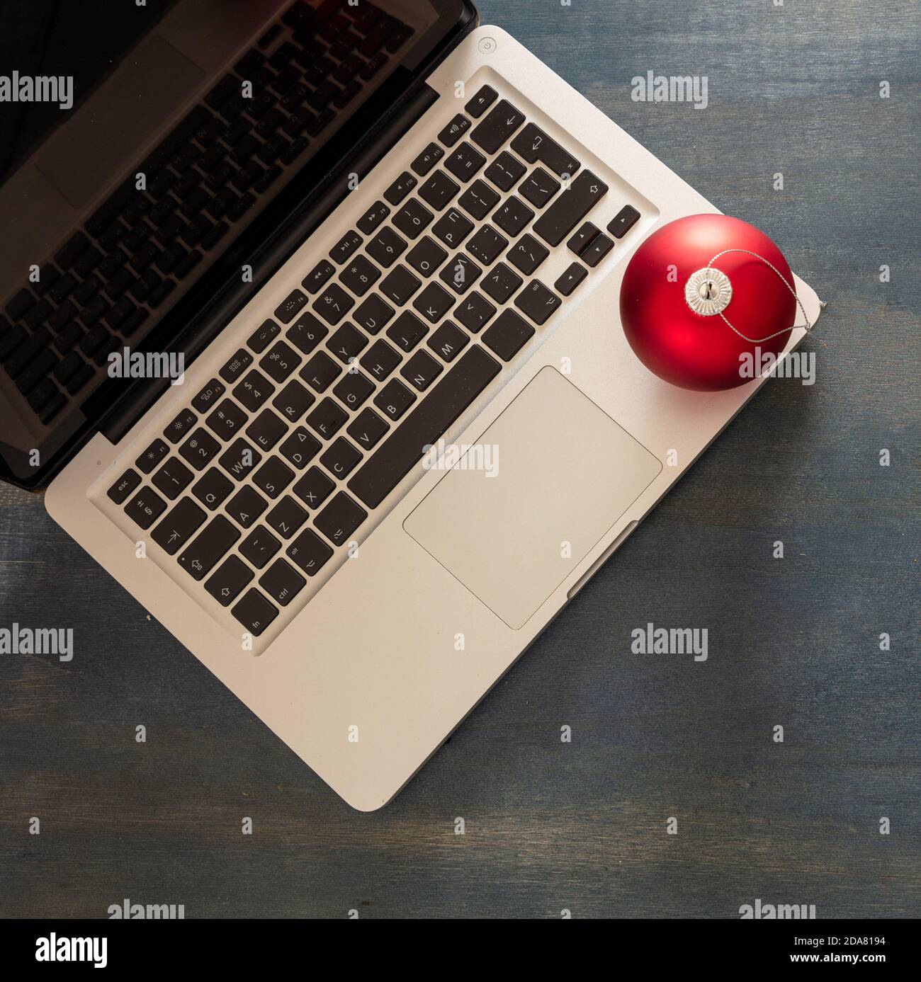 Natale, ufficio chiuso. Scrivania da lavoro, modello per i biglietti per le festività. Laptop e ornamento xmas su sfondo di legno blu, vista dall'alto Foto Stock