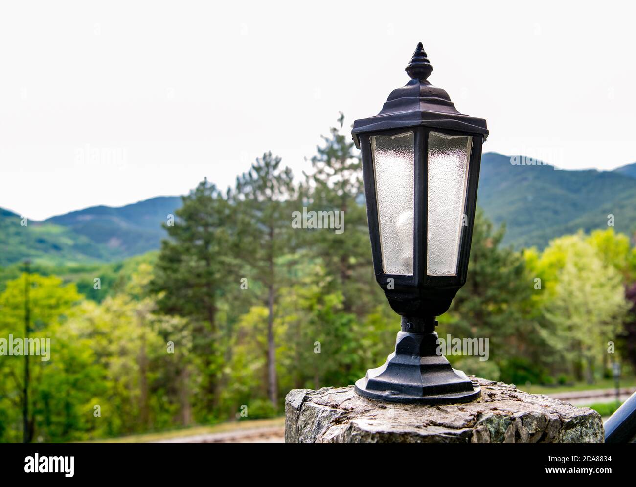 Vecchia lampada da strada, con montagne e alberi nel bacground Foto Stock