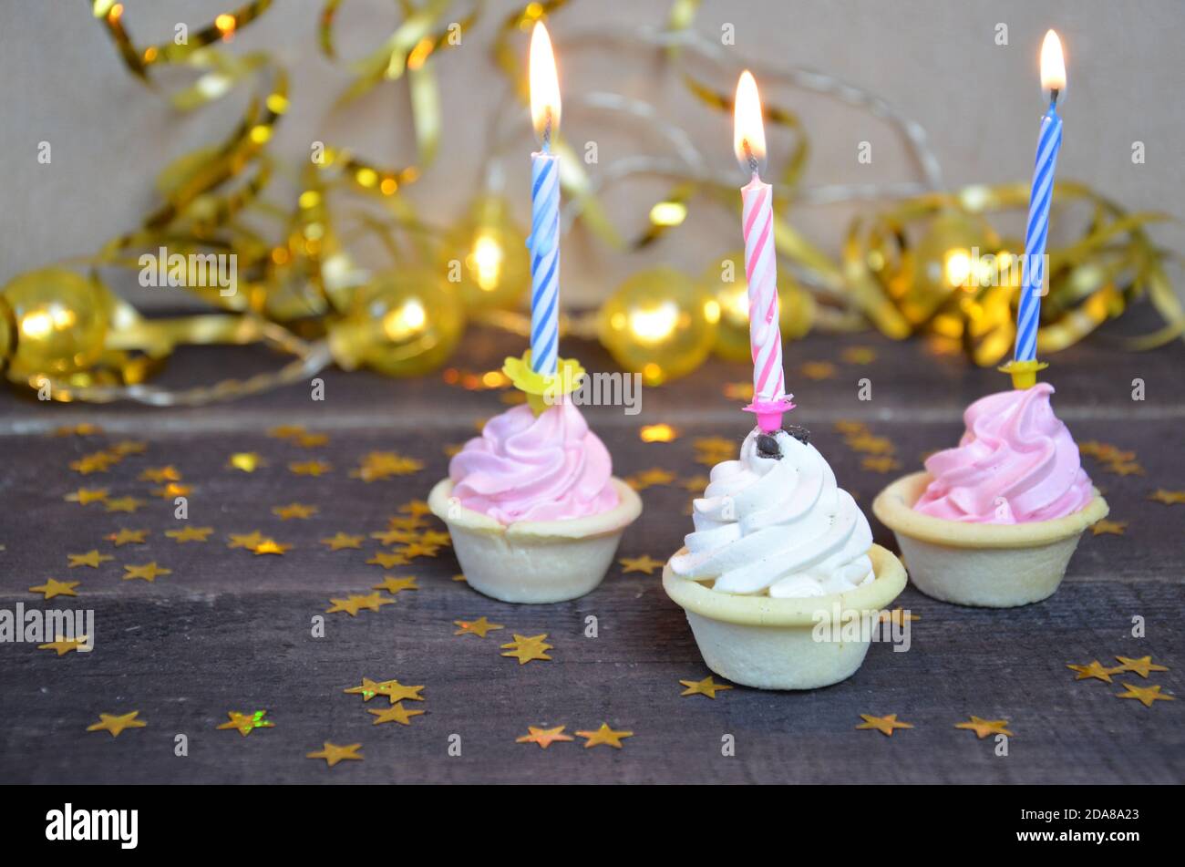 Cupcake con arco e candela felice biglietto di compleanno auguri di vacanze, con streamer e cracker. Foto Stock