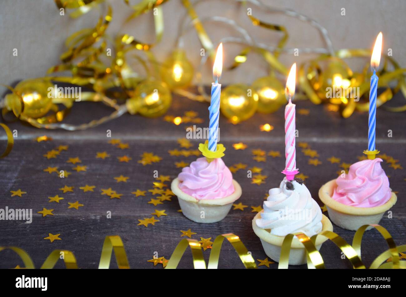 Cupcake con arco e candela felice biglietto di compleanno auguri di vacanze, con streamer e cracker. Foto Stock