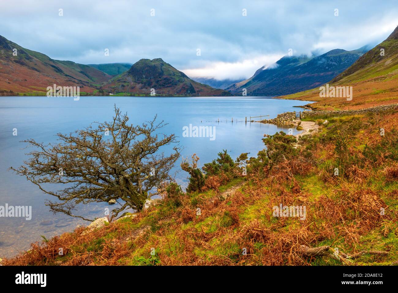 Crummock Water nel nord-ovest Lake District National Park, Cumbria. Le campane intorno a Buttermere in lontananza Foto Stock