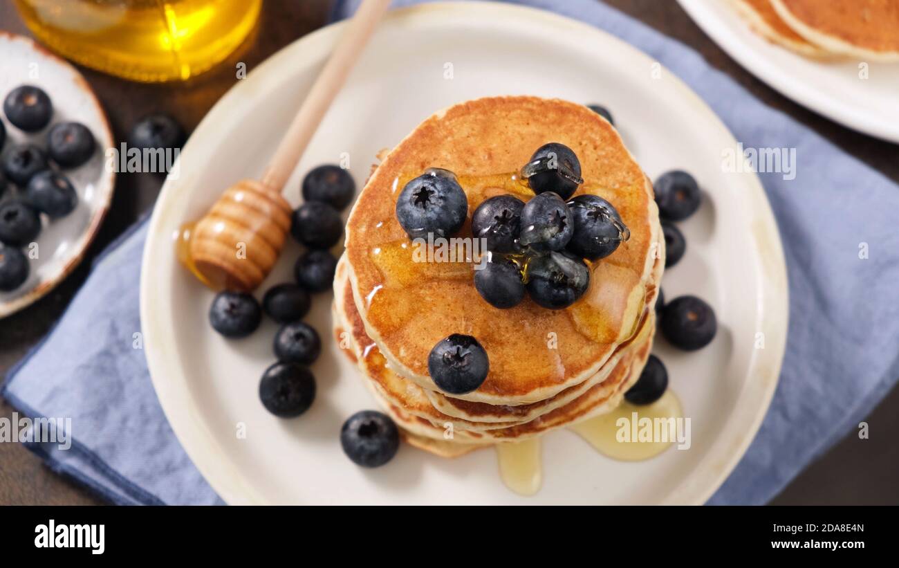 Pancake con mirtilli e miele su una piastra, vista dall'alto Foto Stock