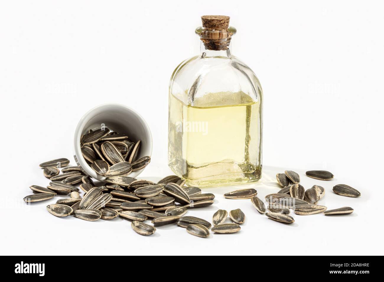 Olio di girasole in bottiglia di vetro e semi isolati su sfondo bianco. Olio da cucina Foto Stock