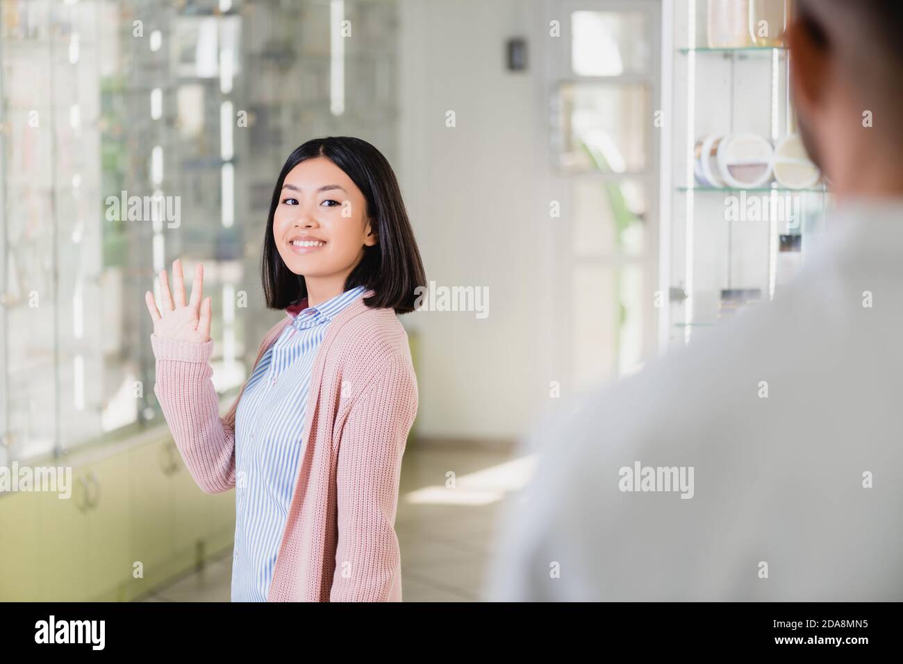 donna asiatica felice che agita mano al farmacista in farmacia Foto Stock