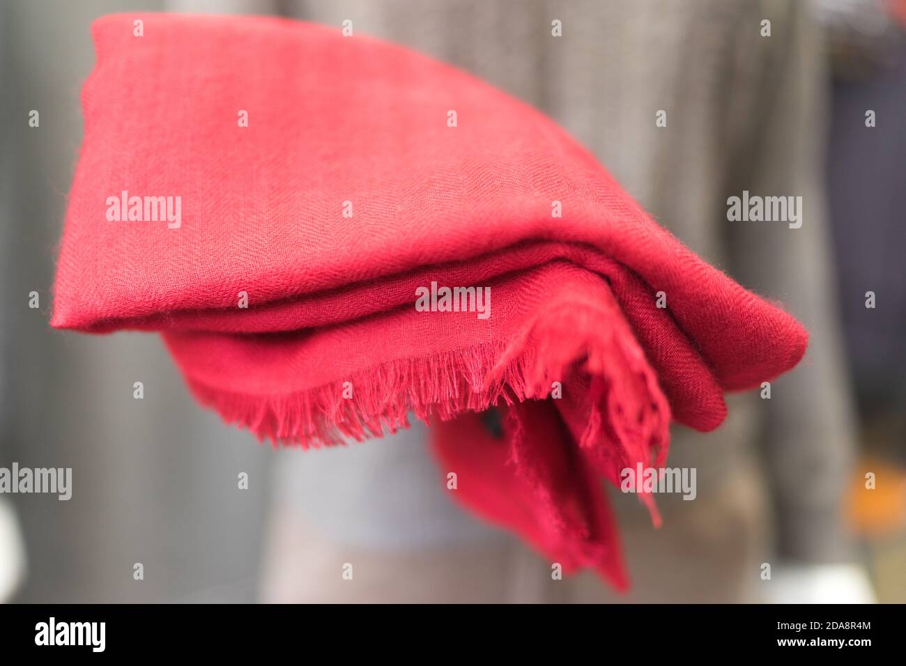 vestiti in un negozio, sciarpa rossa in cashmere in uno showroom, negozio di abbigliamento, prodotti di lana, manichino esponendo elegante panno classico, pezzo di tessuto rosso Foto Stock