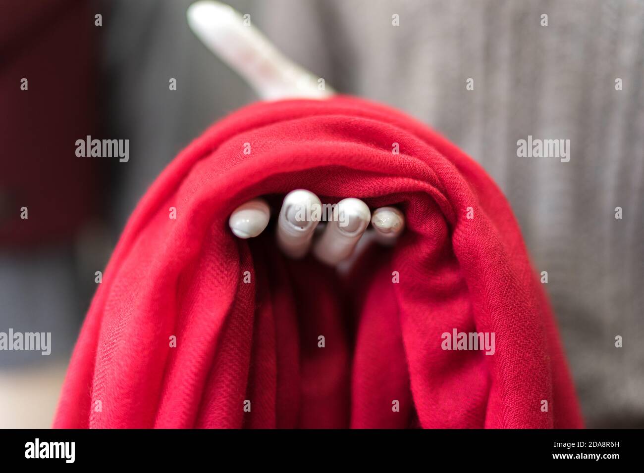 vestiti in un negozio, sciarpa rossa in cashmere in uno showroom, negozio di abbigliamento, prodotti di lana, manichino esponendo elegante panno classico, pezzo di tessuto rosso Foto Stock