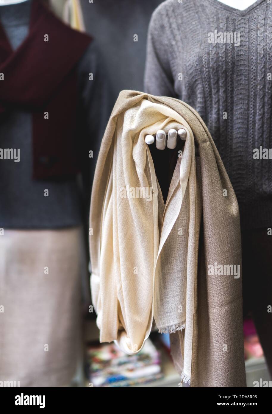 Titolo: Manichino con tessuto di cashmere beige chiaro in mano. Abbigliamento in pashmina naturale. Negozio di lana. Primo piano di una persona che tiene una sciarpa Foto Stock
