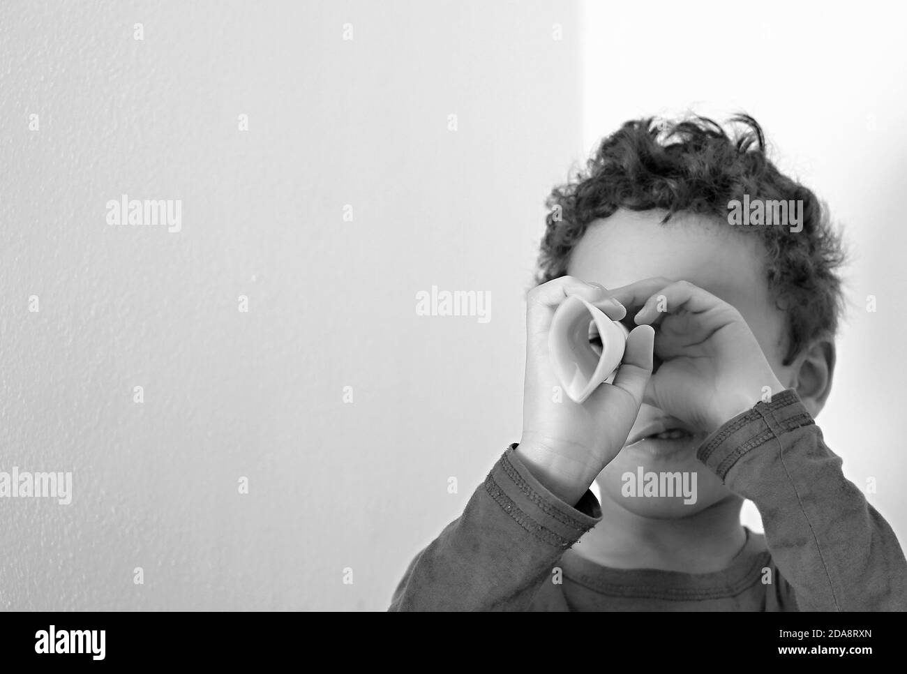 ragazzo guardando attraverso il rotolo di carta binocolo su sfondo bianco foto stock Foto Stock