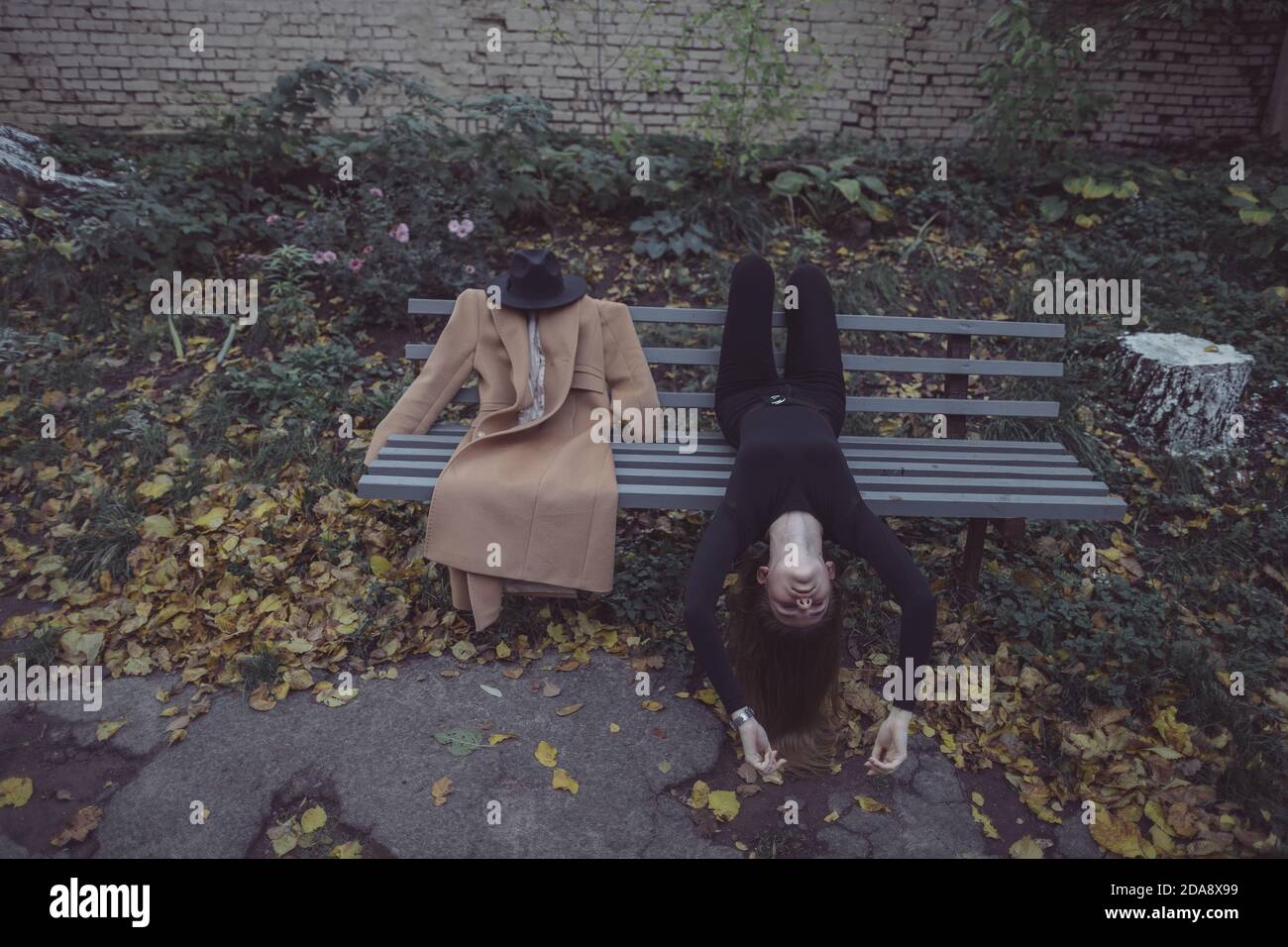 ragazza sdraiata nel parco su una panchina accanto a. il suo ragazzo immaginario Foto Stock