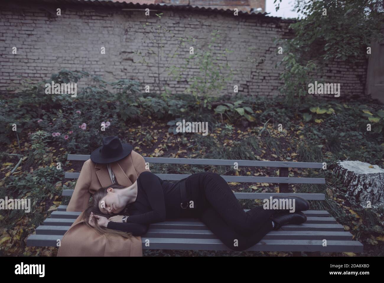 ragazza sdraiata nel parco su una panchina accanto a. il suo ragazzo immaginario Foto Stock