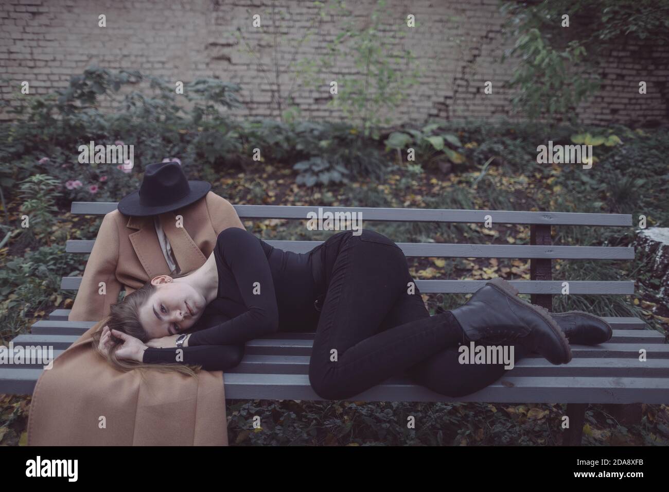 ragazza sdraiata nel parco su una panchina accanto a. il suo ragazzo immaginario Foto Stock