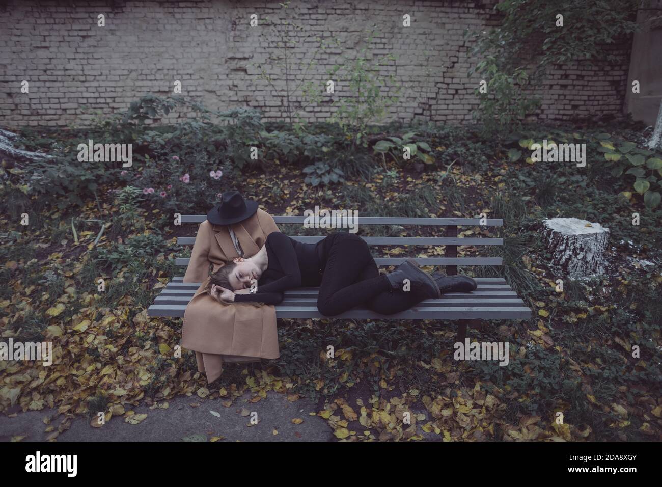 ragazza sdraiata nel parco su una panchina accanto a. il suo ragazzo immaginario Foto Stock