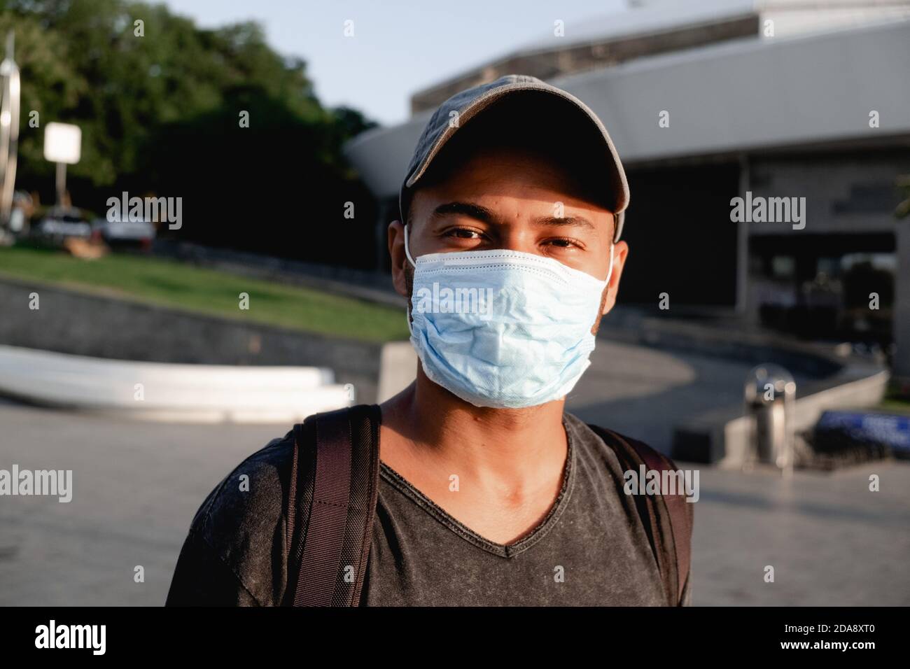 Ritratto di giovane africano con una maschera medica protettiva sul suo volto in strada della città. Concetto di misure preventive e di protezione del coronavirus Foto Stock