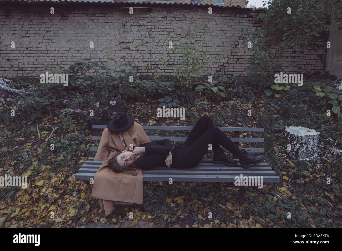 ragazza sdraiata nel parco su una panchina accanto a. il suo ragazzo immaginario Foto Stock