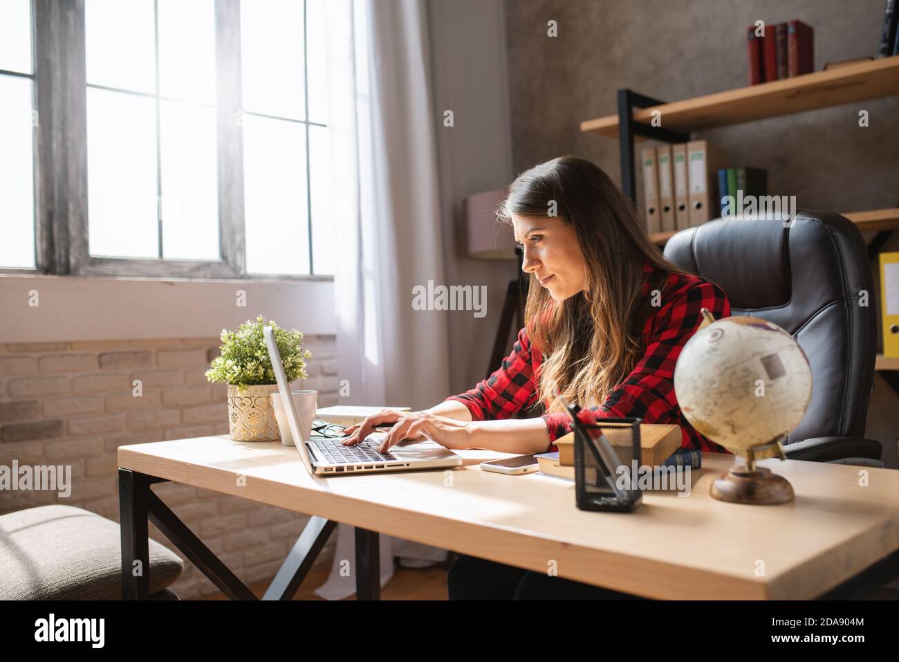 Telelavoratore ragazza lavora a casa con un computer portatile. È nel lavoro astuto dovuto la pandemia di covid-19 Foto Stock