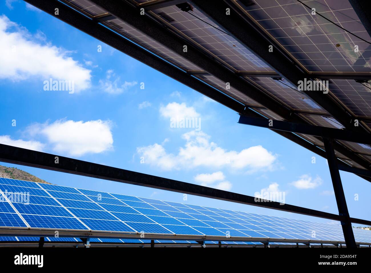 Installazione di pannelli solari in una zona montana con nuvole blu. Foto Stock
