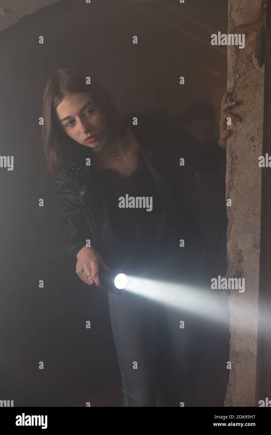 Curiosa giovane ragazza che esplora la cantina scura e creepy con una torcia Foto Stock