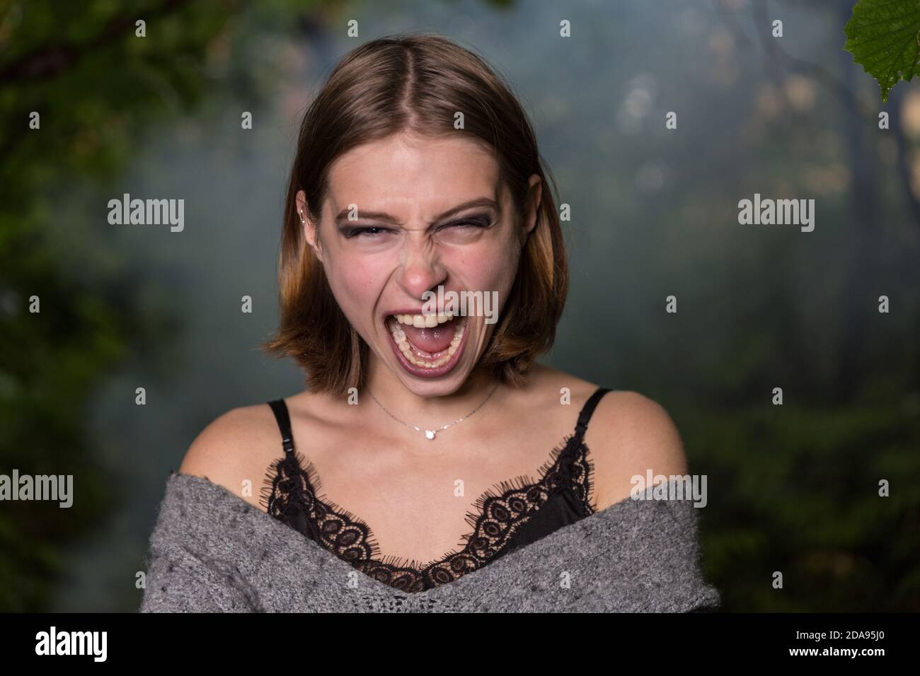 Giovane ragazza urlando in una foresta scura Foto Stock