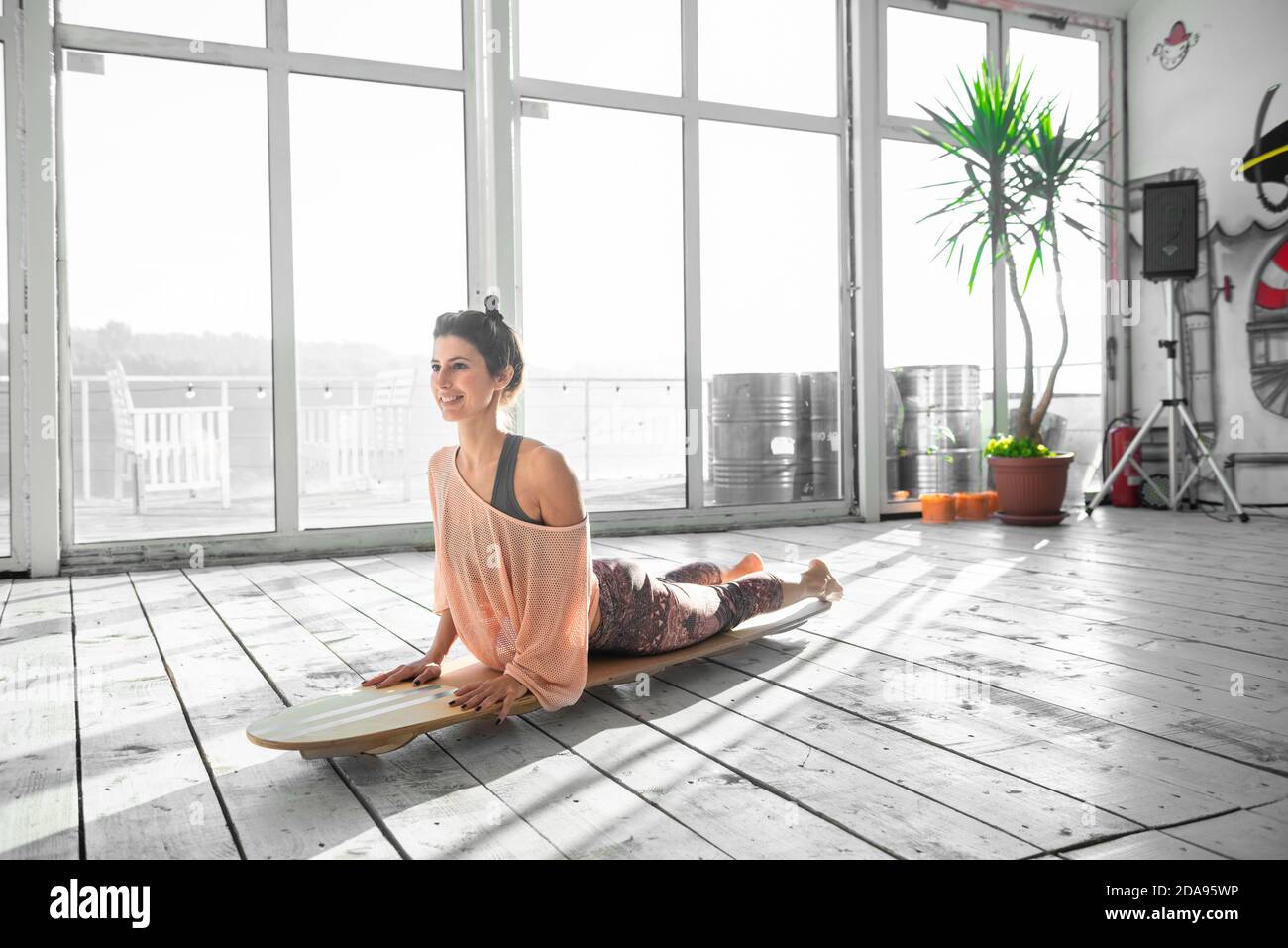 Donna che pratica yoga su una tavola interna SUP Foto Stock