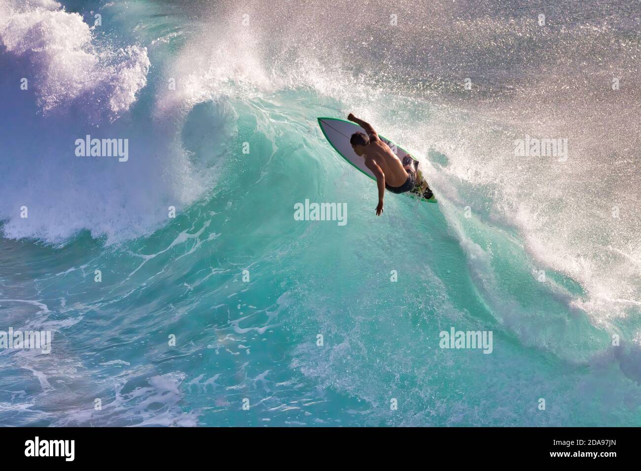 Un giovane surfista carico di difficoltà con una silhouette su un'onda frenetica a Maui. Foto Stock